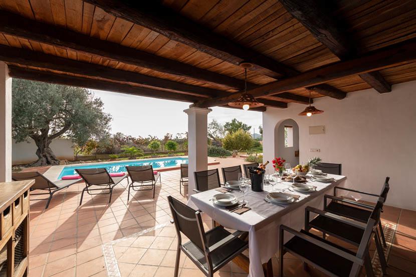Terraza rústica con piscina y comedor al aire libre.